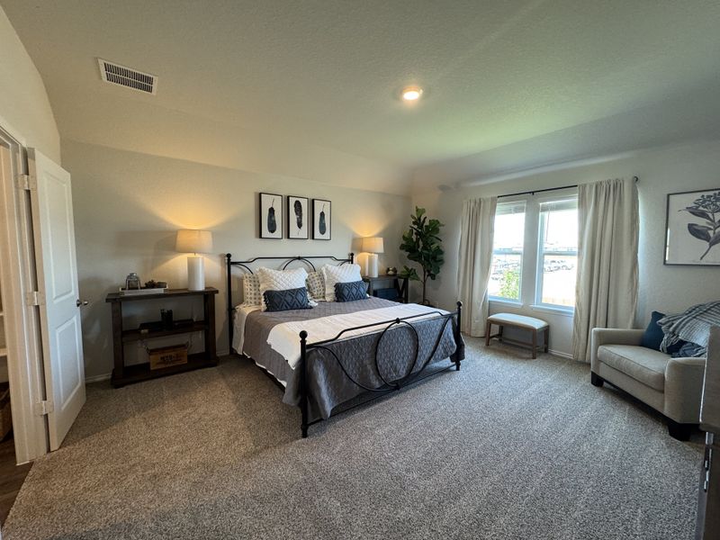 Spacious bedroom with a cozy bed, soft lighting, and elegant decor. Large window with scenic views and plush carpeting.