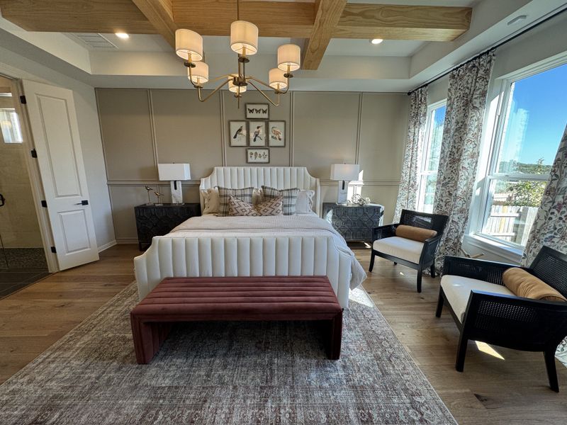 A cozy bedroom featuring a tufted bed, patterned drapes, elegant lighting, and soft wooden accents for a serene atmosphere.