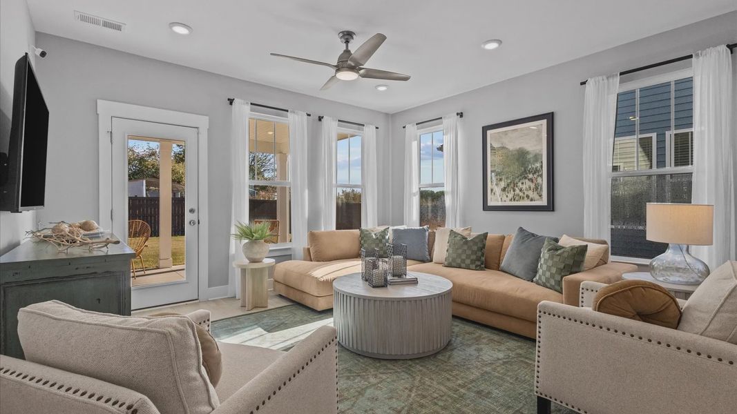 Cozy family room boasting with windows, hardwood flooring, and a ceiling fan at Pleasant Falls by DRB Homes in Moore, SC