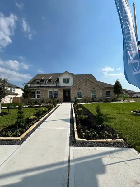 A beautiful stone home with manicured gardens at St. Augustine Meadows by K. Hovnanian® Homes (Mont Belvieu, TX).