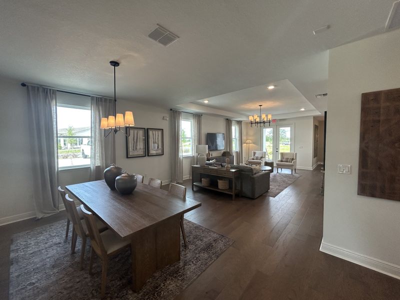 An elegant open-plan living and dining area with wooden flooring, modern lighting, and ample natural light.