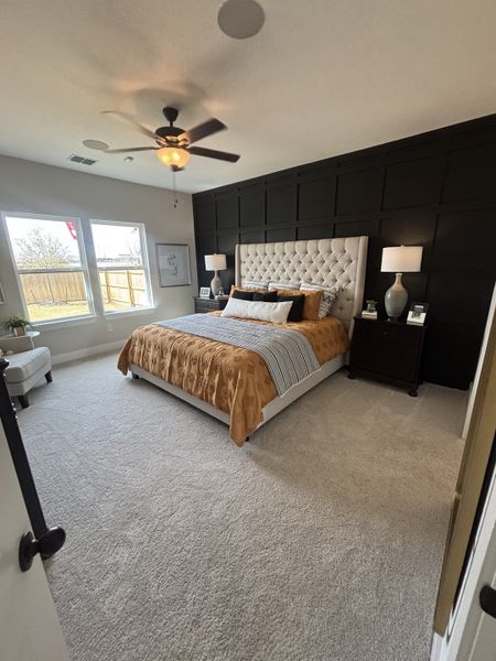 A luxurious and spacious master suite with a black paneled accent wall, a tufted beige headboard, and stylish decor. A luxurious and spacious master suite with a black paneled accent wall, a tufted beige headboard, and stylish decor.