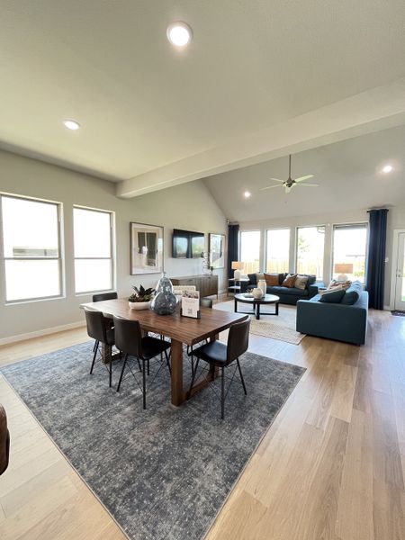 Open-concept living area with modern dining set, cozy seating, and abundant natural light on wooden flooring. Open-concept living area with modern dining set, cozy seating, and abundant natural light on wooden flooring.