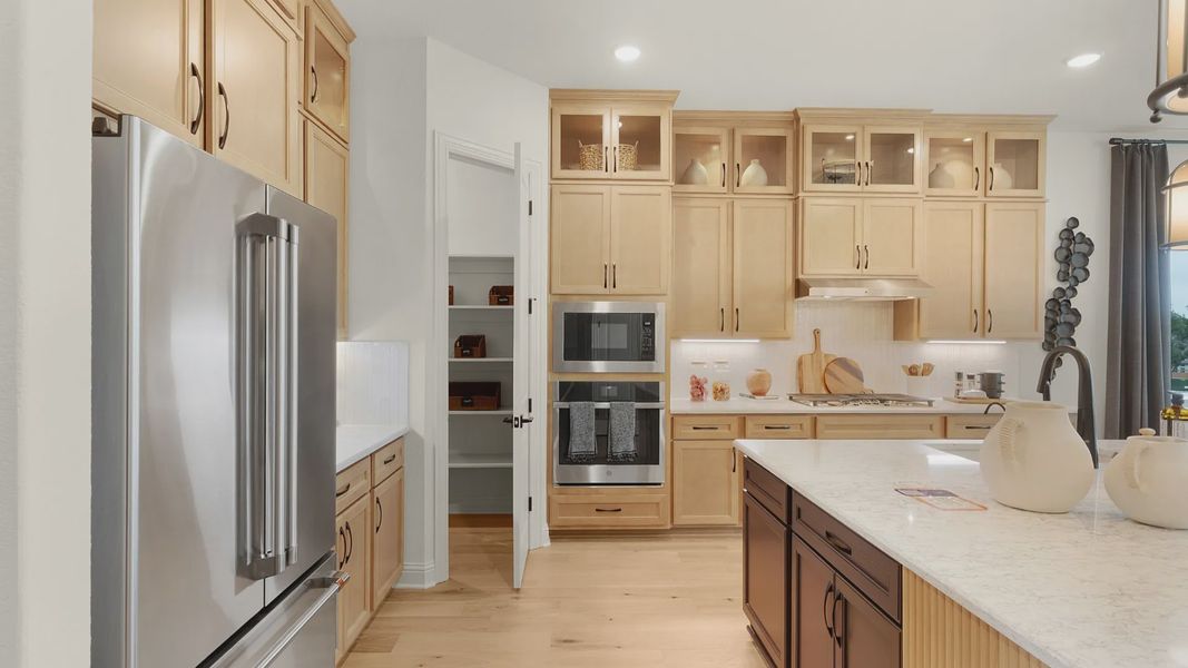 Modern kitchen with spacious corner pantry, cabinet accent lighting, and warm tones