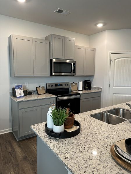 A modern kitchen with granite countertops, sleek gray cabinets, and stainless steel appliances.