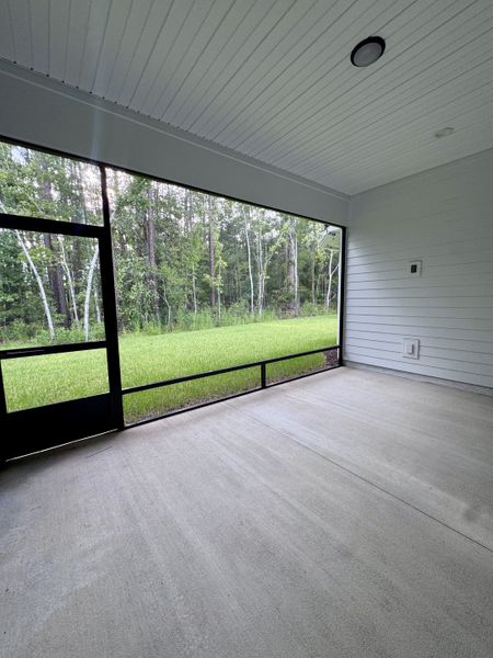 A spacious screened patio with forest views and a sleek concrete floor, perfect for relaxation and nature enjoyment.