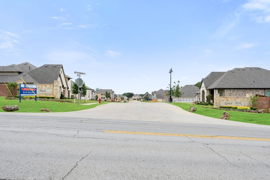 Grace Park neighborhood entrance with stone monument sign, new homes, and a "Now Selling" sign on a sunny day. Grace Park neighborhood entrance with stone monument sign, new homes, and a "Now Selling" sign on a sunny day.