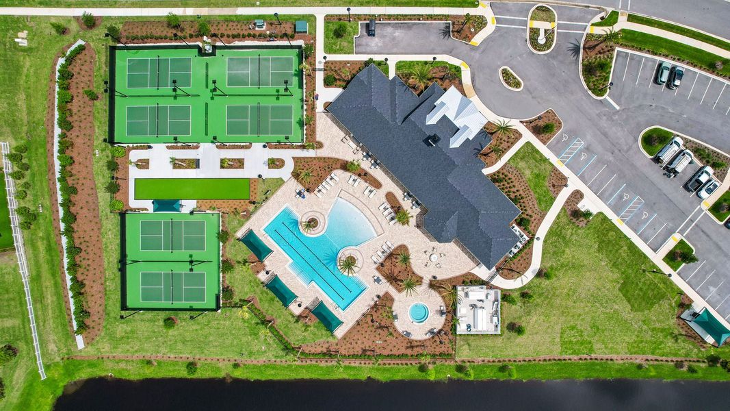 Aerial view of community amenity center with outdoor pool, tennis courts, and parking lot Aerial view of community amenity center with outdoor pool, tennis courts, and parking lot