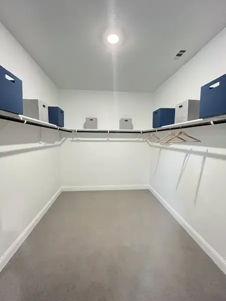 A spacious walk-in closet with sleek shelving, modern storage boxes, and ample hanger space. A spacious walk-in closet with sleek shelving, modern storage boxes, and ample hanger space.