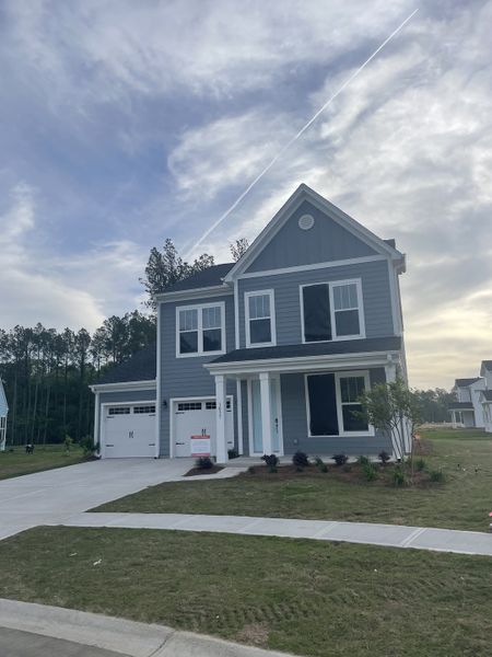 A sleek blue two-story home with a double garage and lovely landscaping in Homecoming by True Homes (Ravenel, SC).