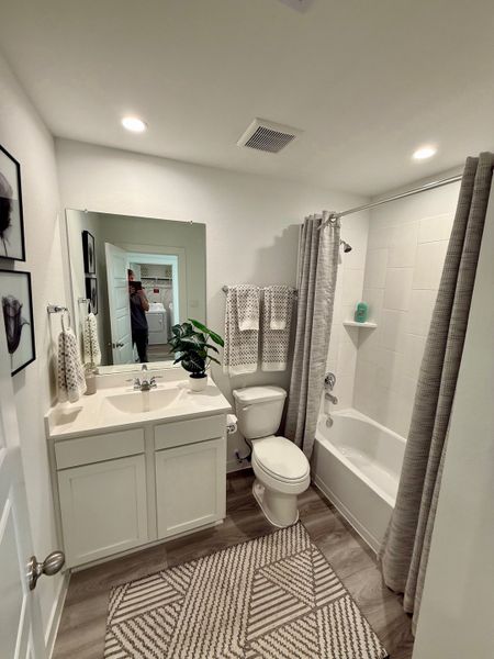 A cozy bathroom featuring a sleek vanity, patterned rug, and warm lighting.