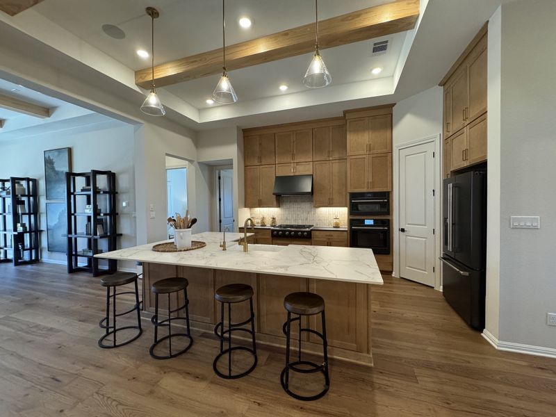 A contemporary kitchen with wood cabinetry, marble island, pendant lighting, and open shelving, creating a warm, inviting atmosphere.