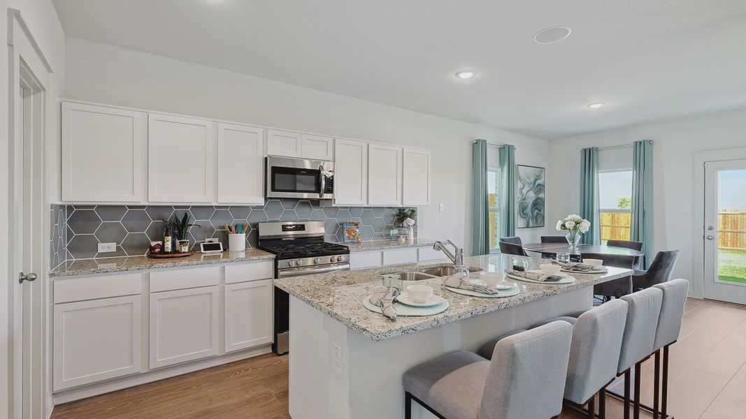 Experience luxury with granite countertops and sleek hexagonal tiles in this exquisite Patriot Estates kitchen. Experience luxury with granite countertops and sleek hexagonal tiles in this exquisite Patriot Estates kitchen.