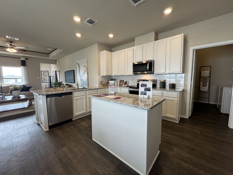 A modern kitchen with sleek white cabinets, granite countertops, and stainless steel appliances.