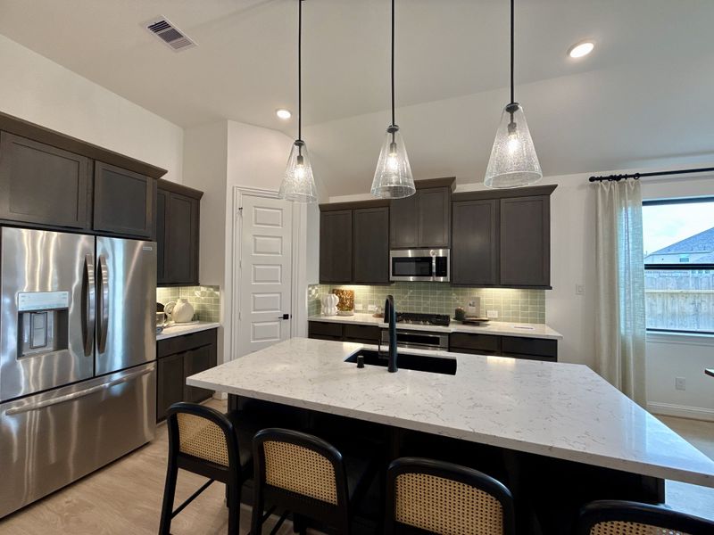 A modern kitchen with sleek cabinetry, a marble island, and pendant lighting. A modern kitchen with sleek cabinetry, a marble island, and pendant lighting.