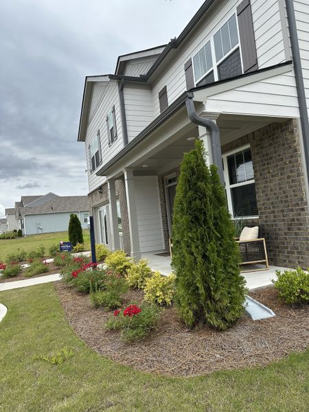 Elegant home with gray shutters and lush landscaping in Oaks at Cedar Grove by D.R. Horton (Fairburn, GA).