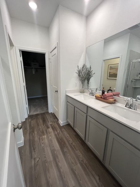 A modern bathroom with dual sinks, elegant wood flooring, and chic decor.