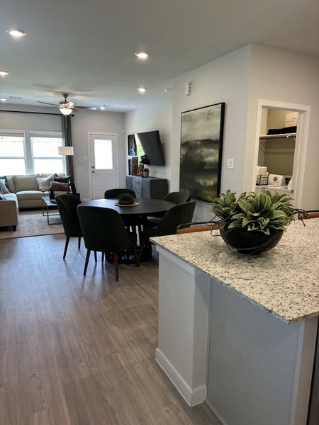 A modern living area with sleek wood flooring, cozy seating, and stylish decor, enhanced by natural light and elegant fixtures.