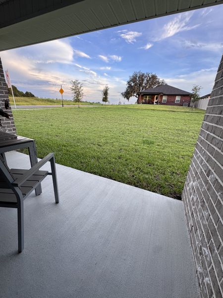 A cozy patio overlooking a vast, green lawn under a scenic sky in Shadow Crest at Rolling Hills by Adams Homes (Green Cove Springs, FL).