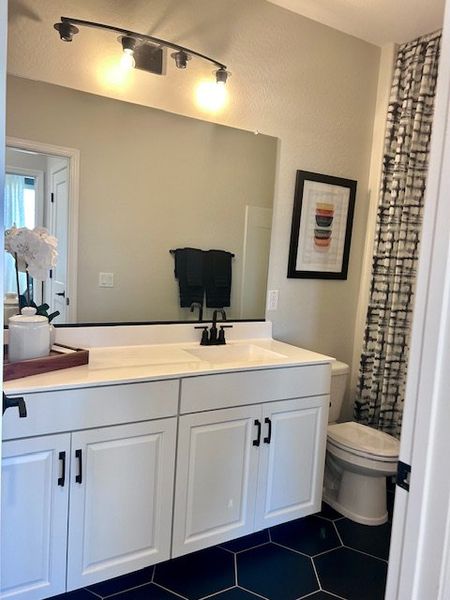 A modern bathroom featuring a sleek white vanity, stylish lighting, and geometric tile flooring. A modern bathroom featuring a sleek white vanity, stylish lighting, and geometric tile flooring.