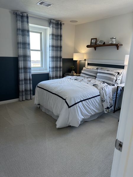 A cozy bedroom featuring a plush bed, striped curtains, and a decorative wall shelf for a serene ambiance.