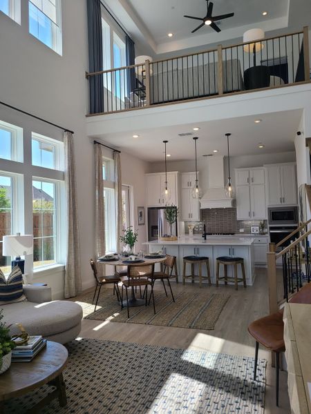 An elegant open-concept living space with high ceilings, large windows, a modern kitchen, and loft area. An elegant open-concept living space with high ceilings, large windows, a modern kitchen, and loft area.