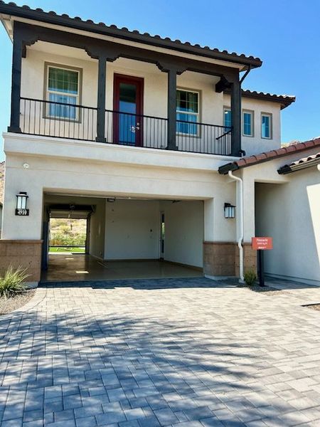 A modern home with a terrace and driveway in the Highlands at Verrado by Capital West Homes (Buckeye, AZ).