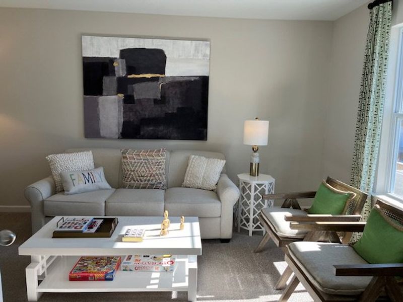 A cozy living room featuring a plush sofa, abstract art, and stylish armchairs for a relaxing atmosphere.