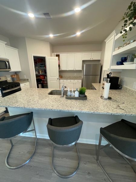 A modern kitchen with granite countertops, sleek appliances, and cozy seating at the island.