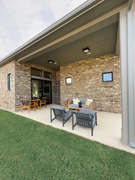 A cozy covered patio with brick walls, modern seating, and a lush lawn perfect for relaxation. A cozy covered patio with brick walls, modern seating, and a lush lawn perfect for relaxation.
