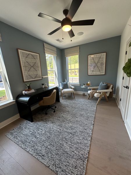 A modern home office with sleek furniture, decorative art, and ample natural light.