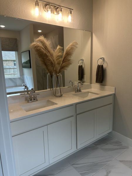 A modern bathroom features a sleek dual vanity, elegant backsplash, and bright lighting, enhancing its stylish ambiance.