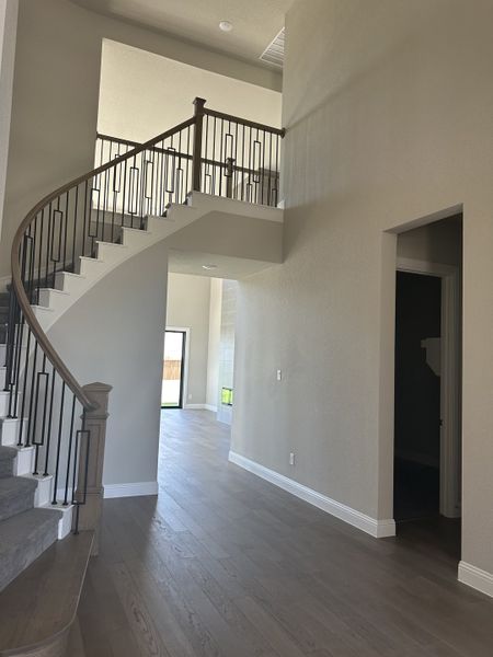 A spacious entryway with a grand, curved staircase, sleek railings, and elegant hardwood flooring. A spacious entryway with a grand, curved staircase, sleek railings, and elegant hardwood flooring.