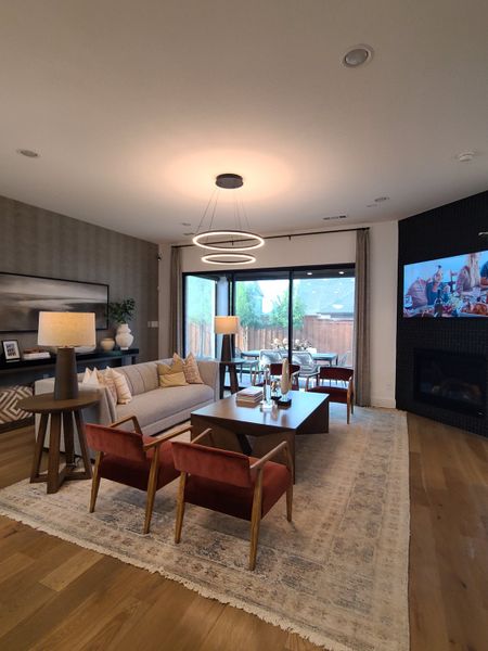 A modern living room with cozy seating, contemporary lighting, and a sleek fireplace.
