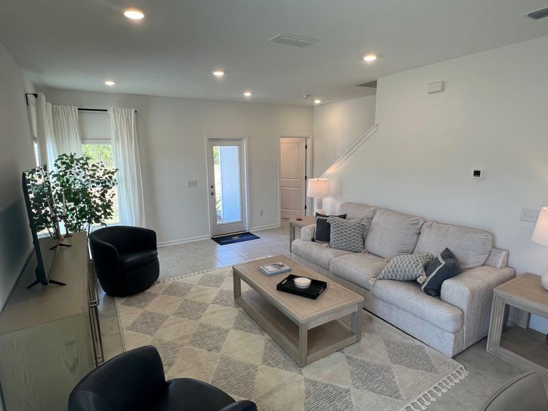 A cozy living room with a plush sofa, modern armchairs, and soft lighting, creating a warm and inviting atmosphere.