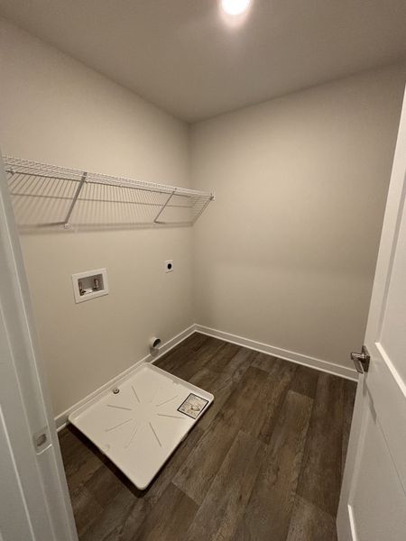 A utility room with wood flooring, open shelving, and plumbing hookups, ready for customization. A utility room with wood flooring, open shelving, and plumbing hookups, ready for customization.
