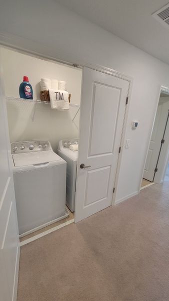 A compact laundry room with efficient appliances and open shelving, featuring modern amenities for convenience.