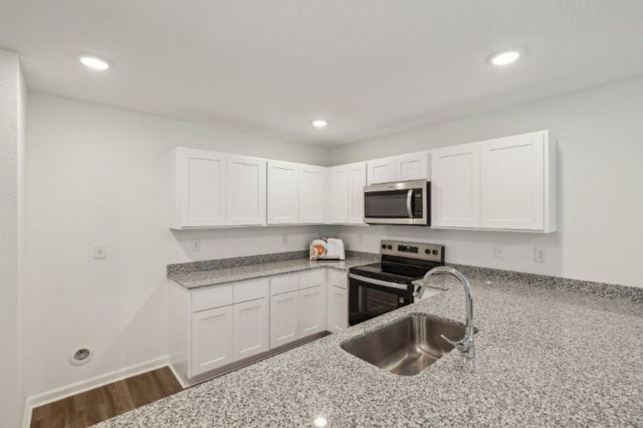 A kitchen with white cabinets.