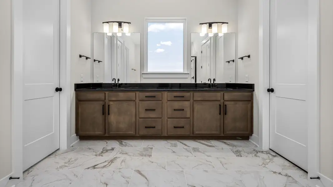 Luxurious bathroom with dark cabinetry, dual vanity, and a window Luxurious bathroom with dark cabinetry, dual vanity, and a window