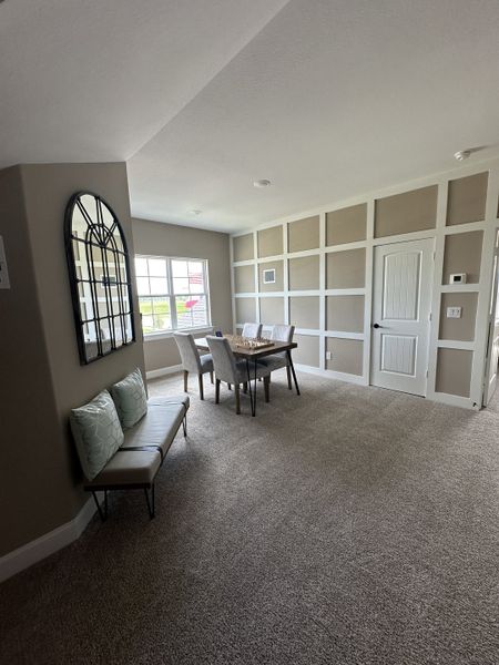 A bright room with plush carpet, panel walls, a modern dining table, and elegant seating. A bright room with plush carpet, panel walls, a modern dining table, and elegant seating.