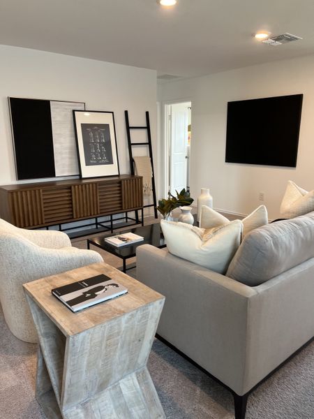 A modern living room with a cozy gray sofa, stylish artwork, elegant ladder shelf, and minimalist decor.