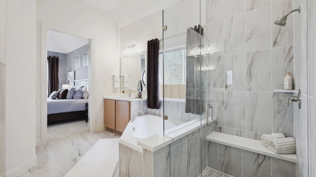 Indulge in this spa-like master bath with exquisite marble tiles and sleek glass shower in The Oaks.