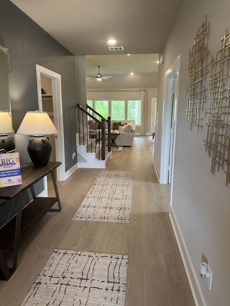 A modern hallway with elegant lighting, decorative wall art, and a view into a cozy living area with neutral tones.