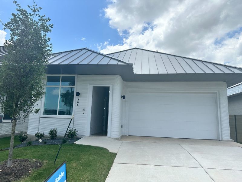A modern white home with a sleek metal roof and landscaped yard in Wolf Ranch: Genesis Collection by Lennar (Georgetown, TX).