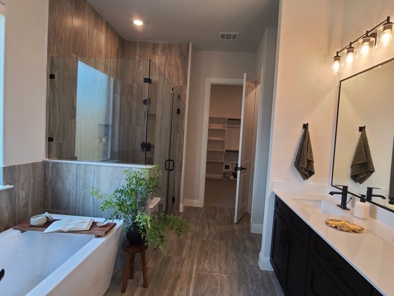 A luxurious bathroom with a freestanding tub, glass-enclosed shower, dual vanity, and elegant lighting.