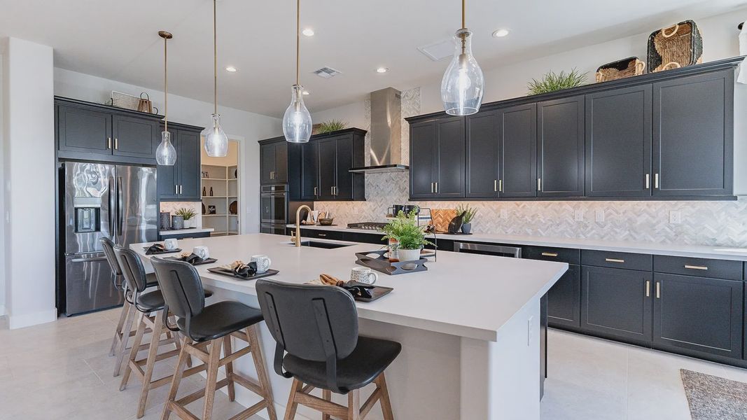 Elegant black cabinets, marble backsplash, and quartz island define this Windrose community kitchen masterpiece.