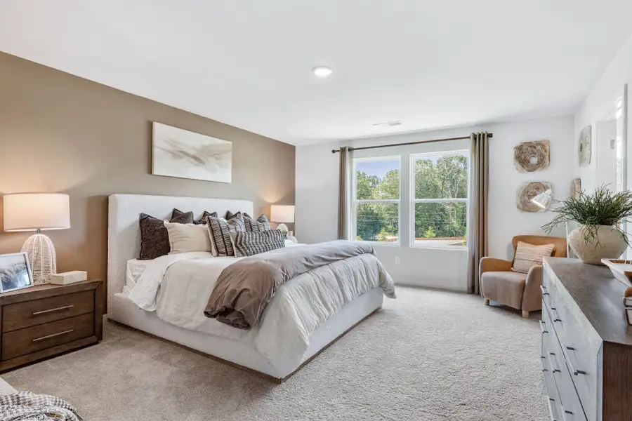 A bedroom with a bed and a chair.