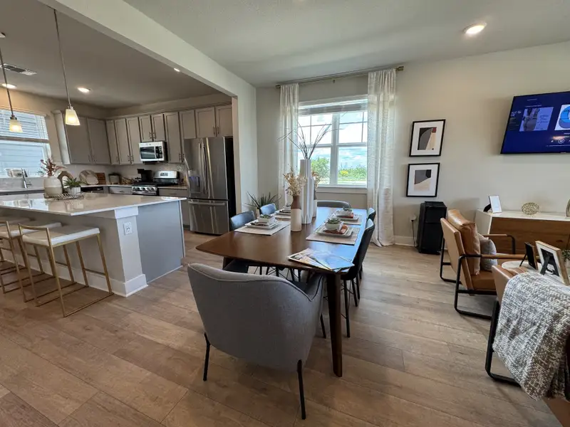 Modern open-plan dining and kitchen area featuring sleek cabinetry, stainless appliances, and stylish decor with natural light.