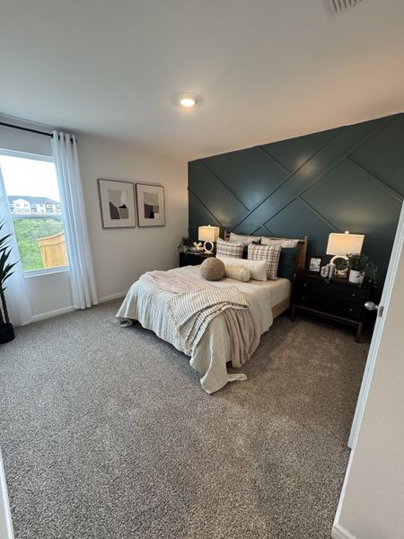 A cozy bedroom with a modern teal accent wall, plush carpeting, and elegant décor. A cozy bedroom with a modern teal accent wall, plush carpeting, and elegant décor.