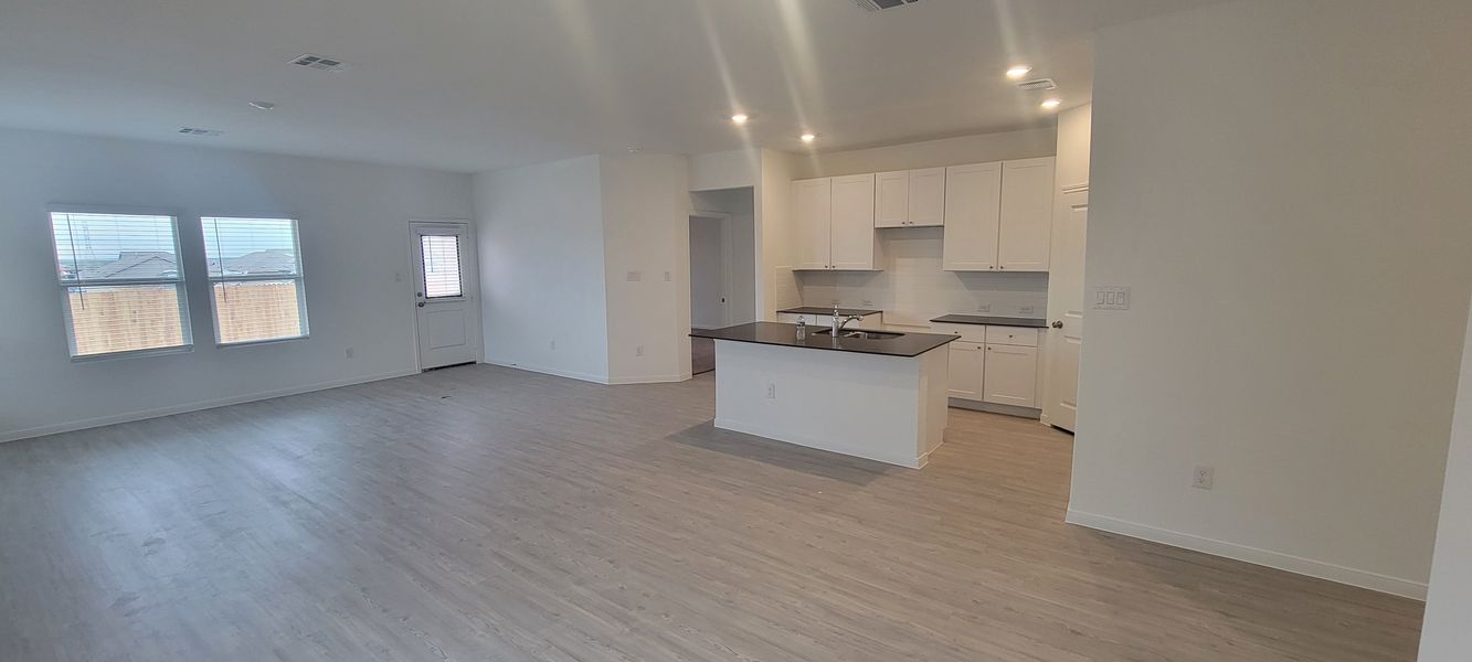 A spacious open-plan kitchen with sleek cabinetry, a central island, and bright natural lighting.